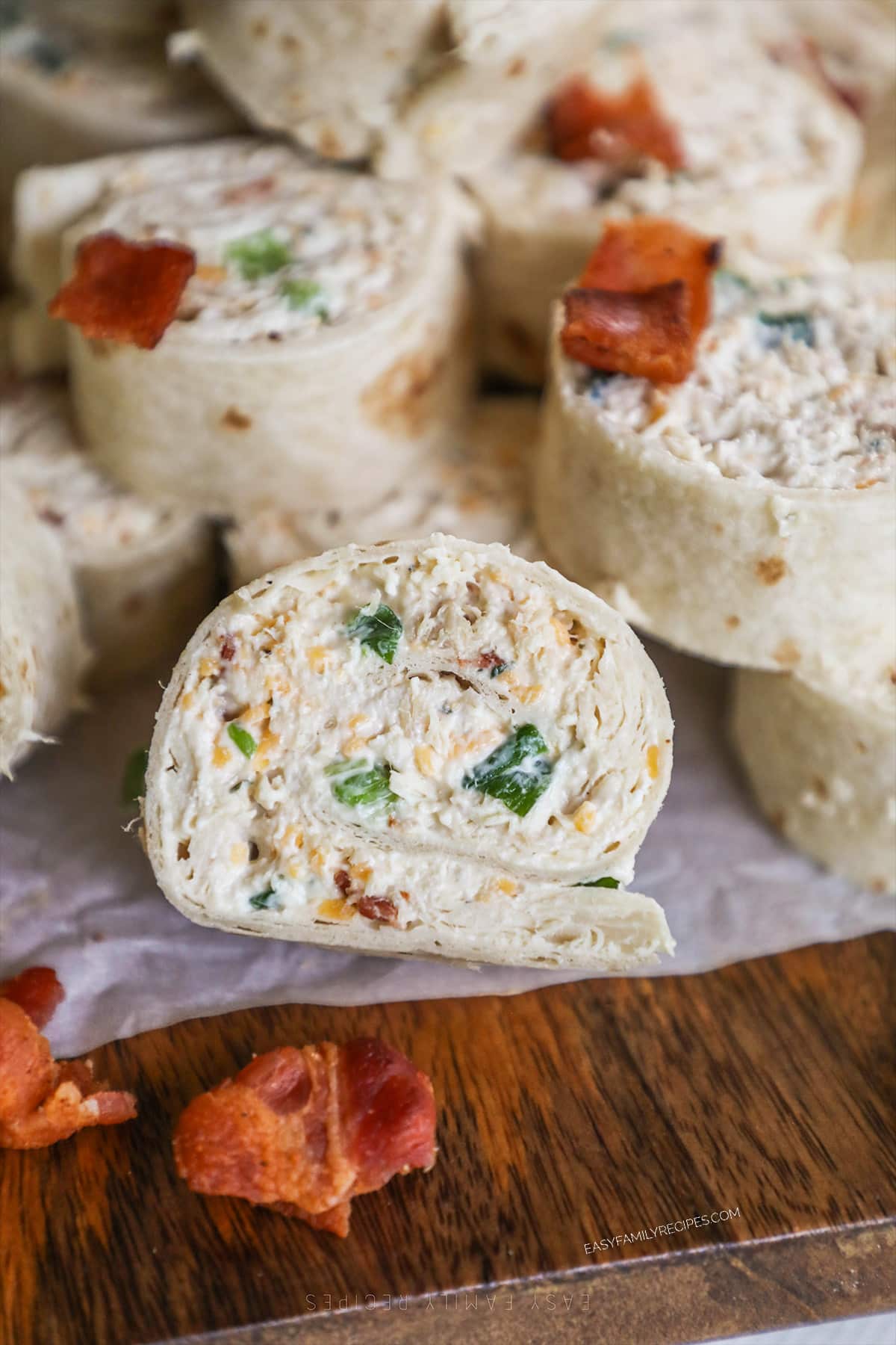 Chicken Bacon Ranch Pinwheels with bacon on the top, on a piece of parchment paper.