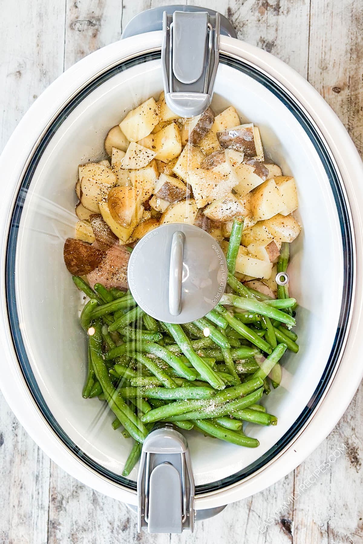 Slow cooker ready to cook chicken and potatoes with green beans.