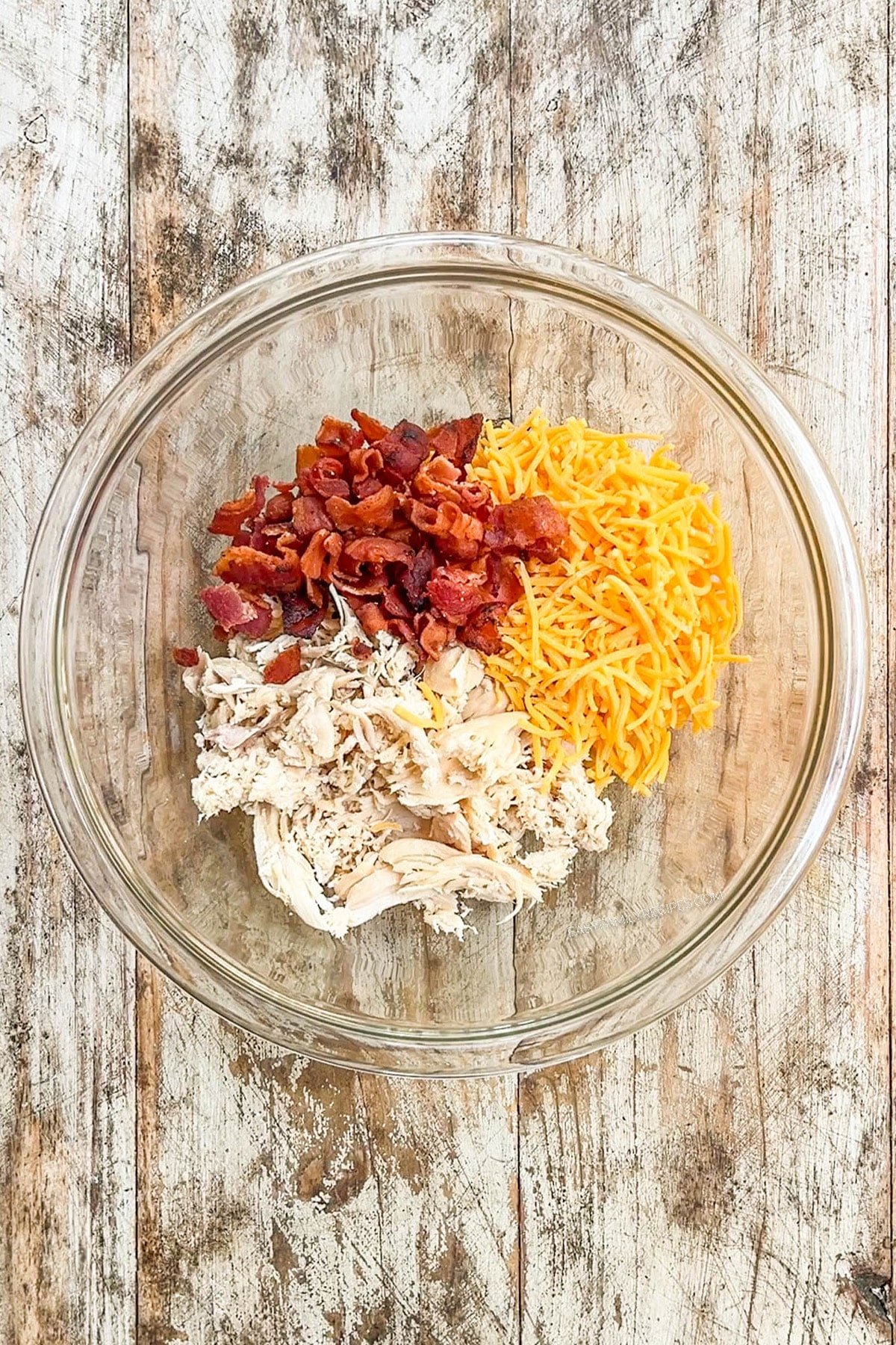 Cheese, chicken, and bacon in a bowl for chicken bacon ranch pinwheels.