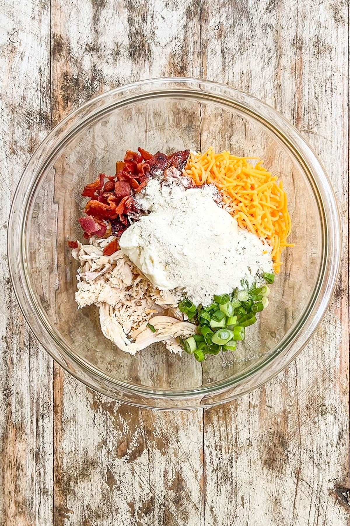 Ingredients for the filling for chicken bacon ranch pinwheels in a clear glass bowl.