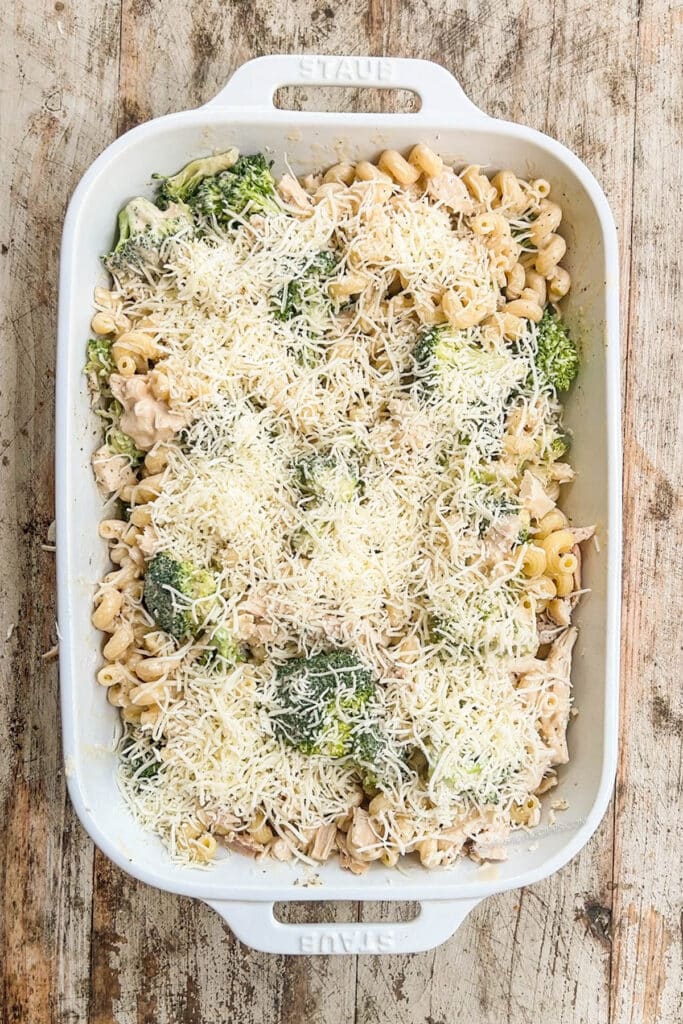 alfredo pasta and broccoli in a casserole dish topped with cheese.