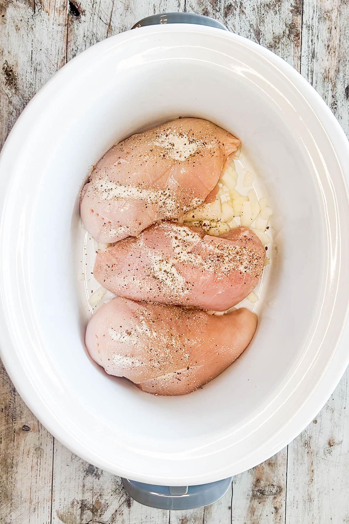 How to make slow cooker chicken and potatoes step 2: add chicken breast and season the chicken.