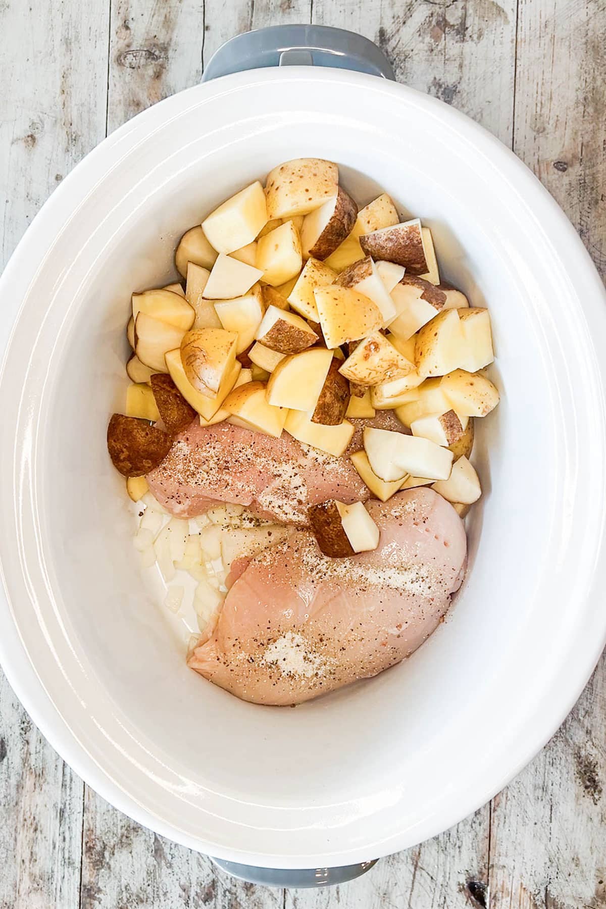 How to make slow cooker chicken and potatoes step 3: top chicken with potatoes.