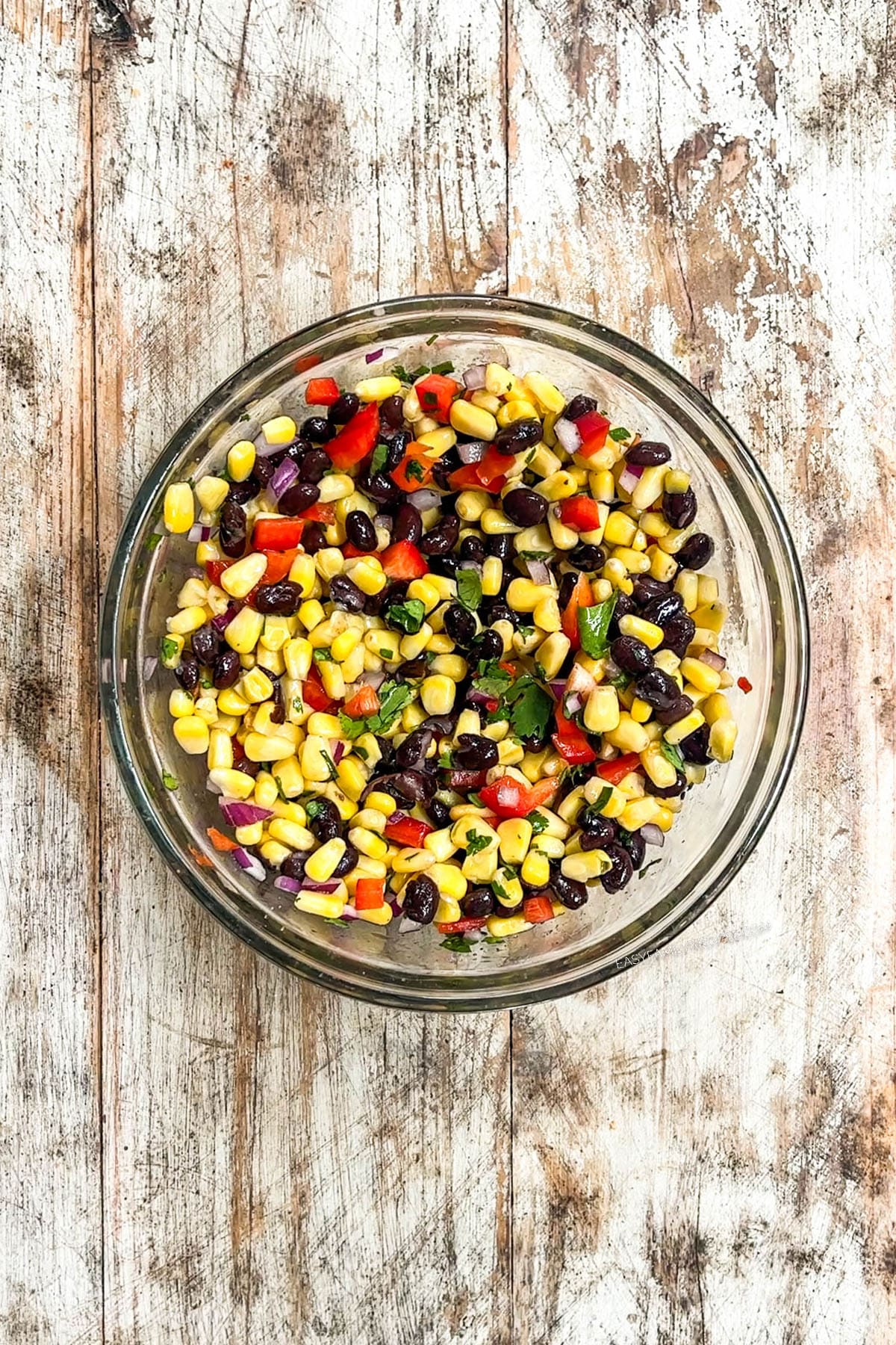 Black bean and corn salsa in a mixing bowl on a distressed wood background.