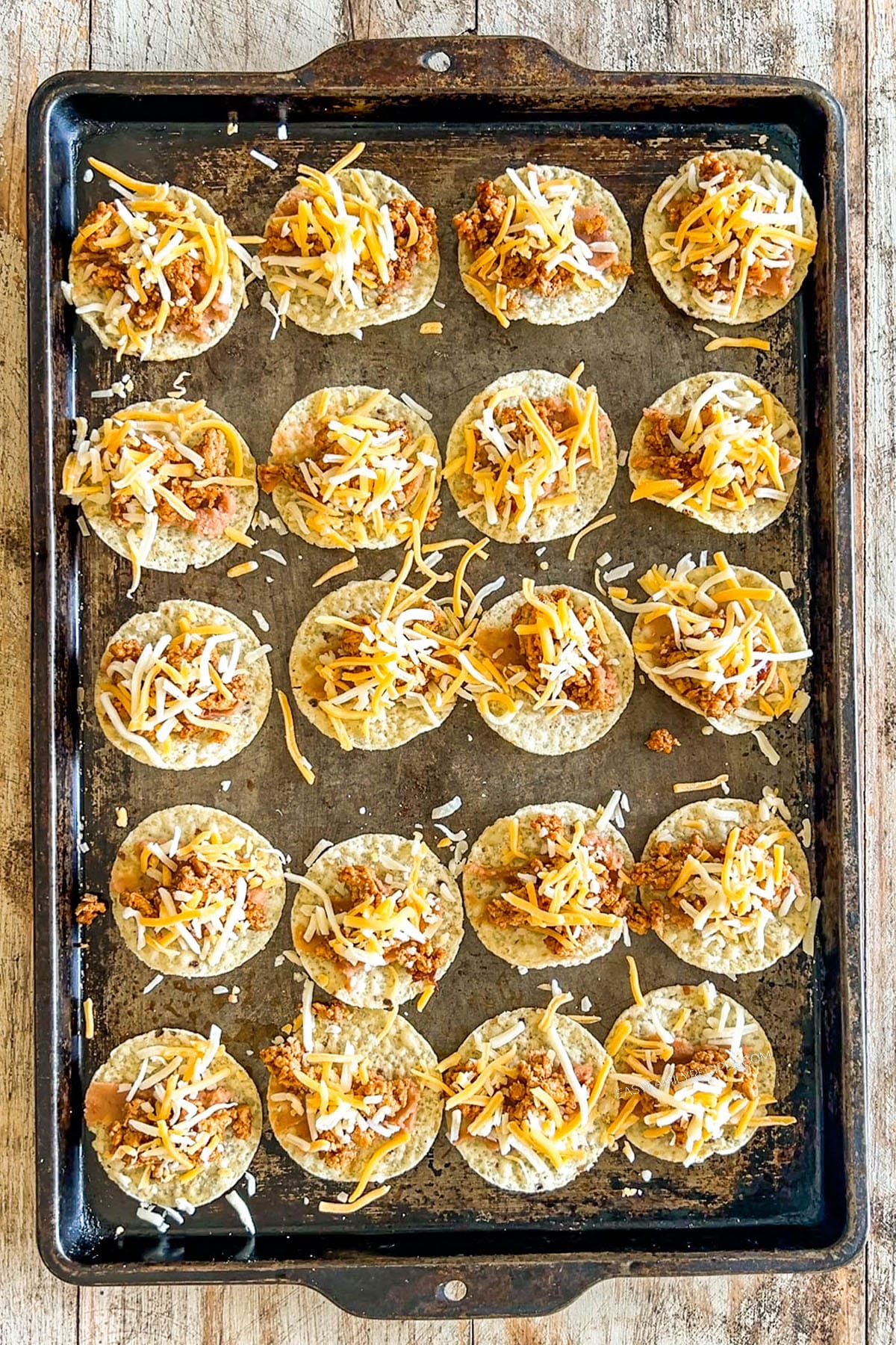 Step 3 of making Tiny Tacos - each chip is topped with cheese.