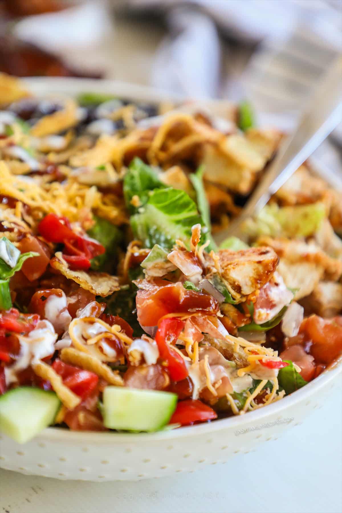 A close-up of BBQ chicken bowls in a white bowl with a silver fork.