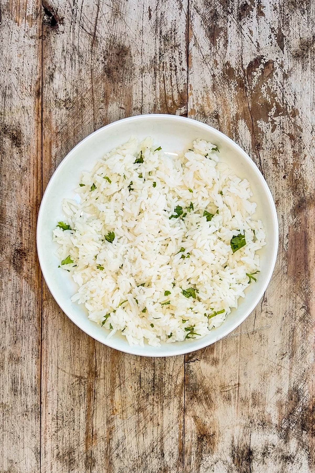 Step one of how to make BBQ chicken bowls: Add cilantro lime rice to a shallow bowl.