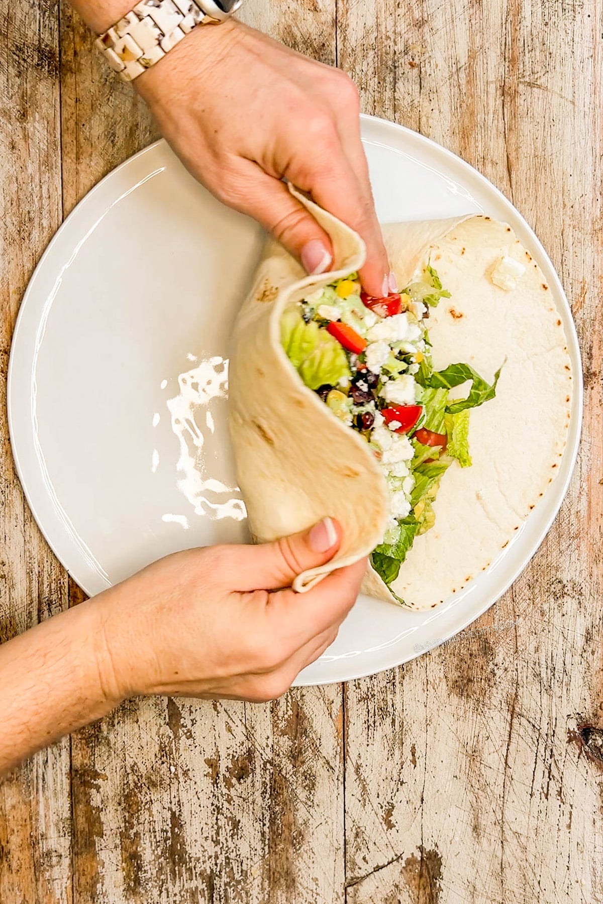 a tortilla being folded over wrap fillings. 