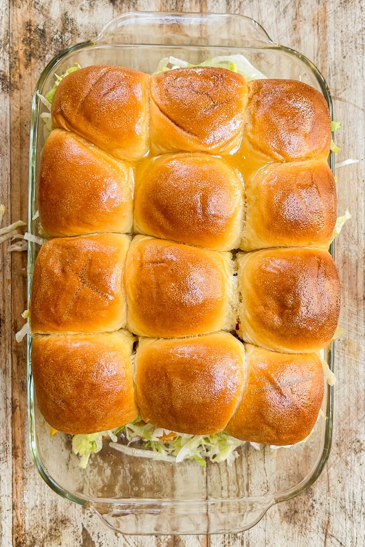 Top view of chicken tender sliders in a glass casserole dish.