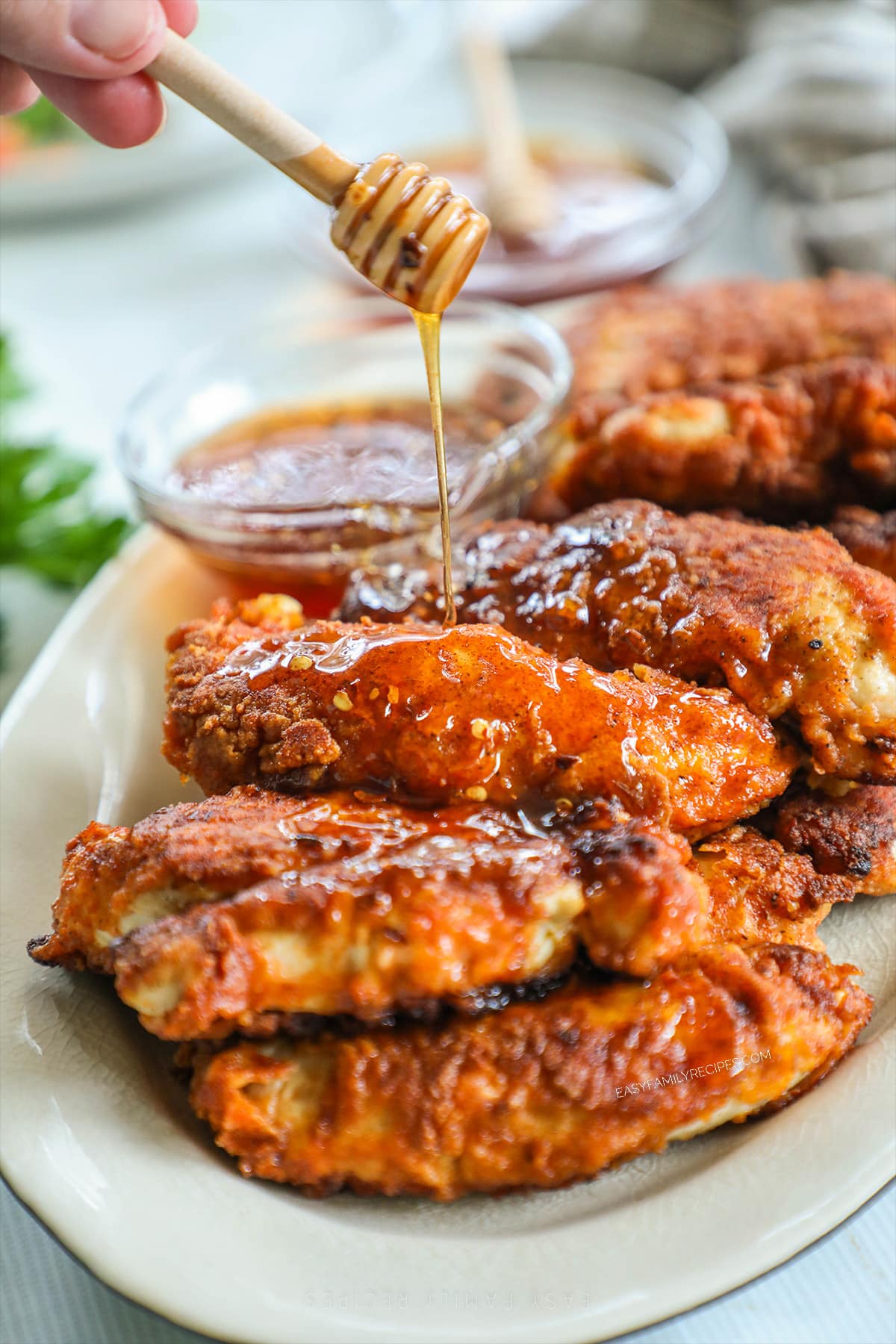 Step 6 for hot honey chicken tenders: Drizzle the hot honey over the fried chicken tenders.