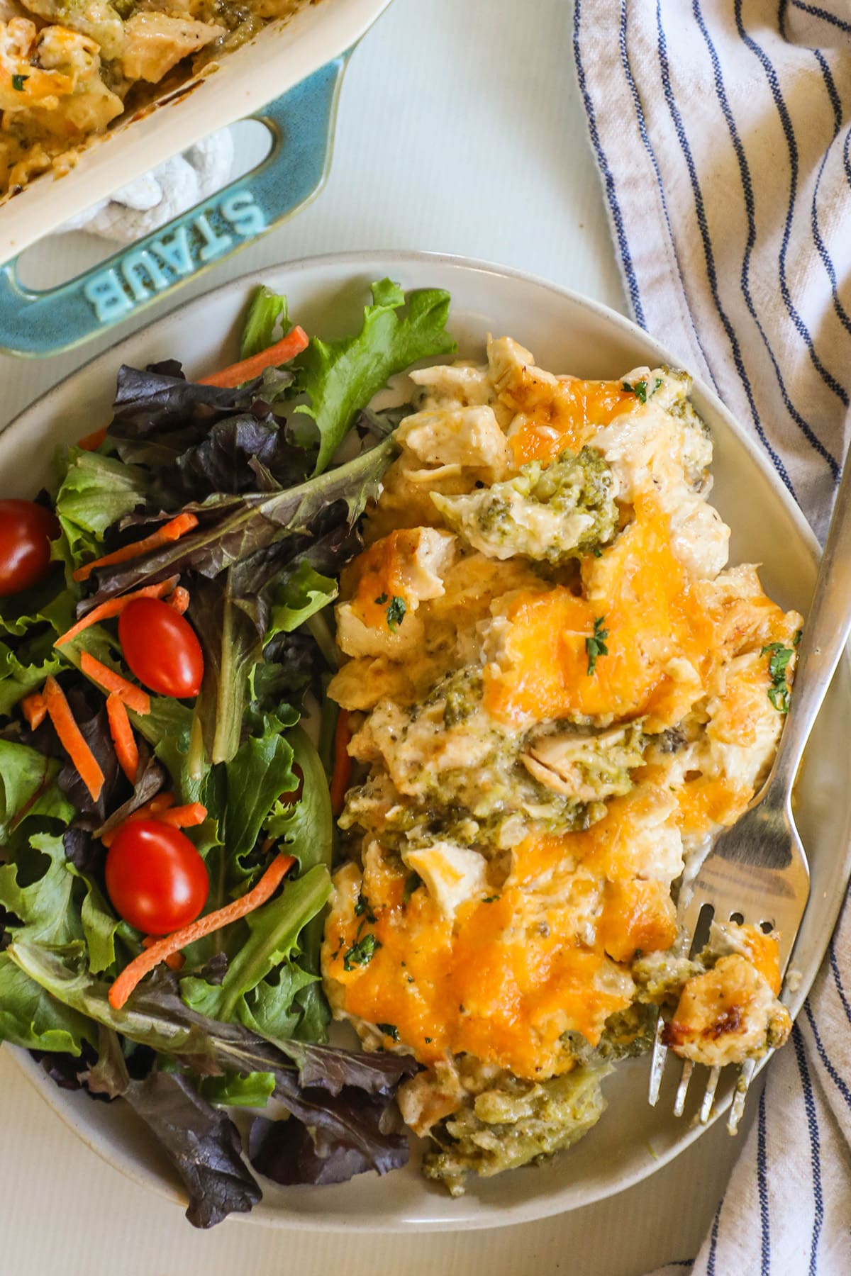 A serving of Nixon Chicken with a side salad on a white plate with a silver fork alongside.