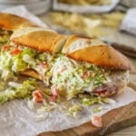 A side view of an Italian Grinder Sandwich on parchment paper.