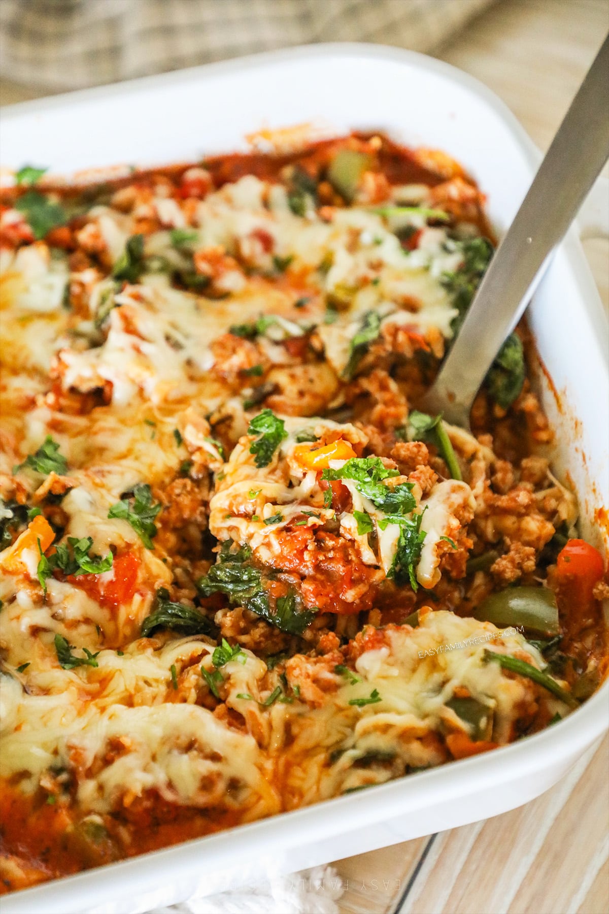 A silver serving spoon scoops out a serving of turkey stuffed pepper casserole.