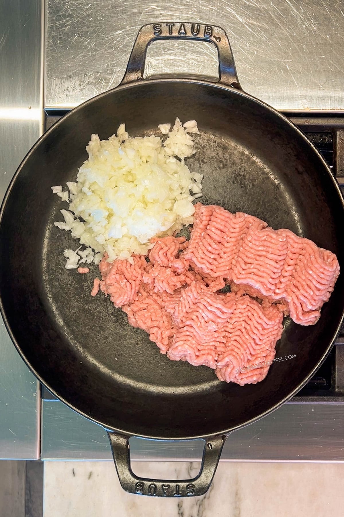 Ground turkey and ingredients in a cast-iron pan, being cooked for Turkey Stuffed Pepper Casserole.