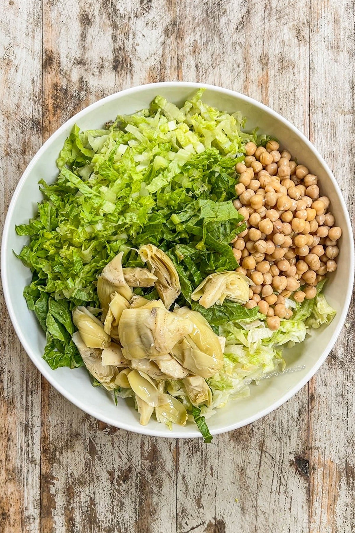 lettuce, chickpeas, and artichoke hearts in a bowl.