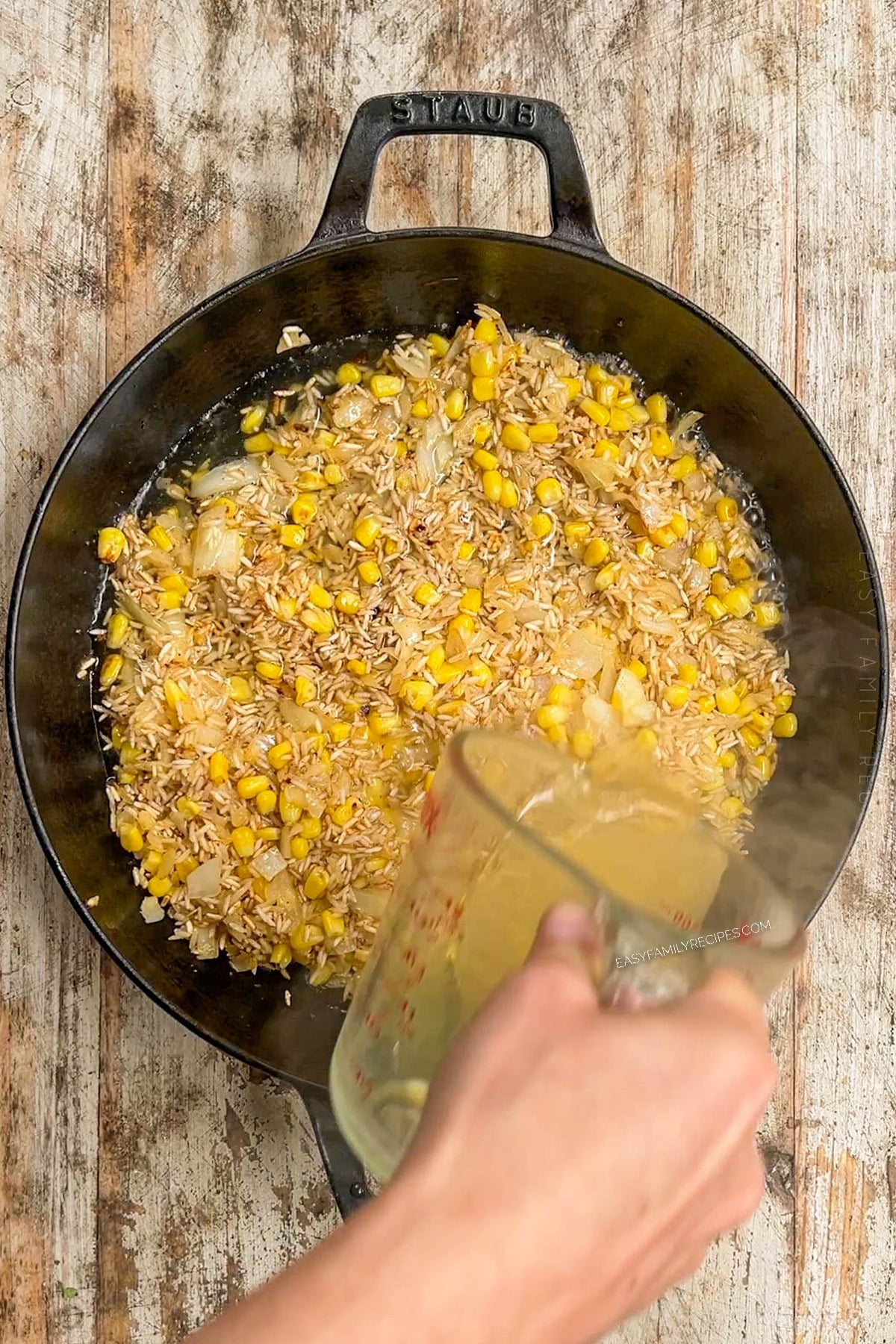 broth being poured into a skillet.