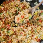 above image of a wooden spoon scooping a portion of Southwest rice out of a skillet.