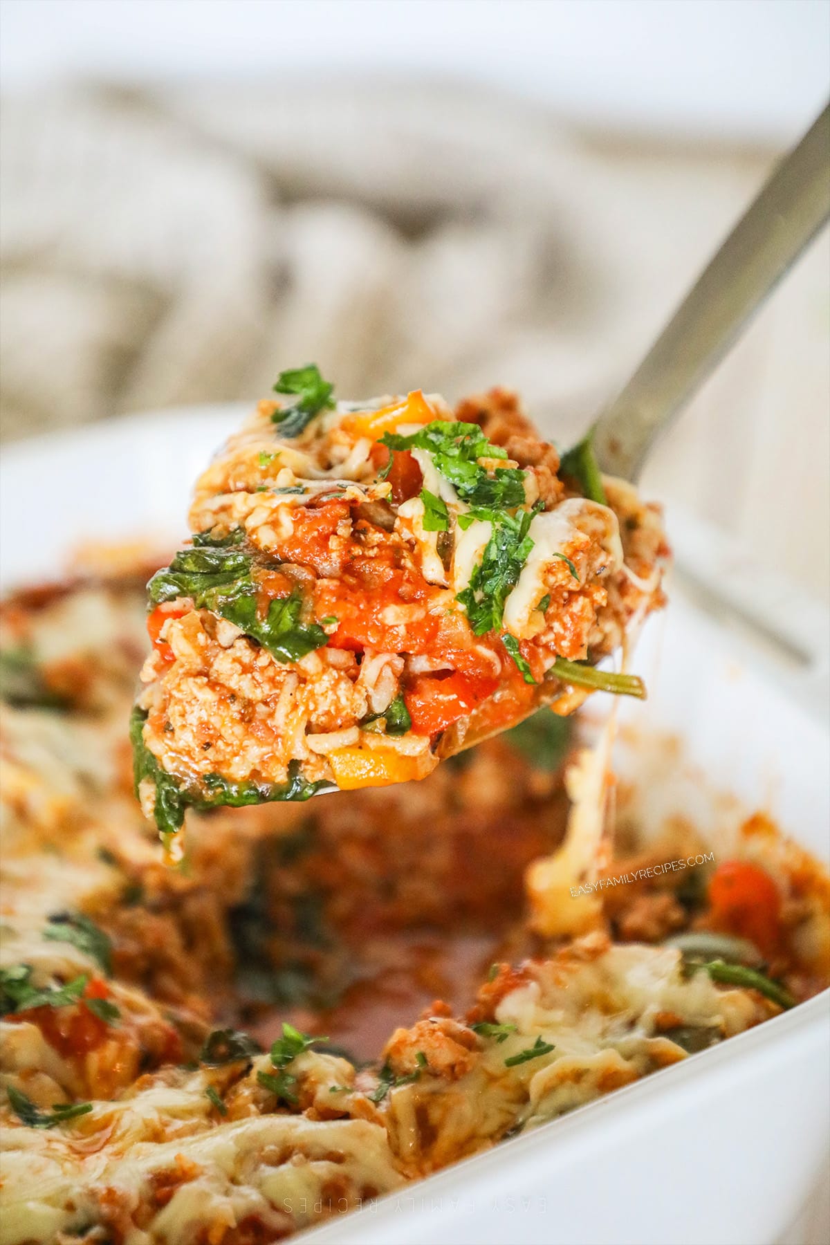 A silver serving spoon scoops out a serving of turkey stuffed pepper casserole.