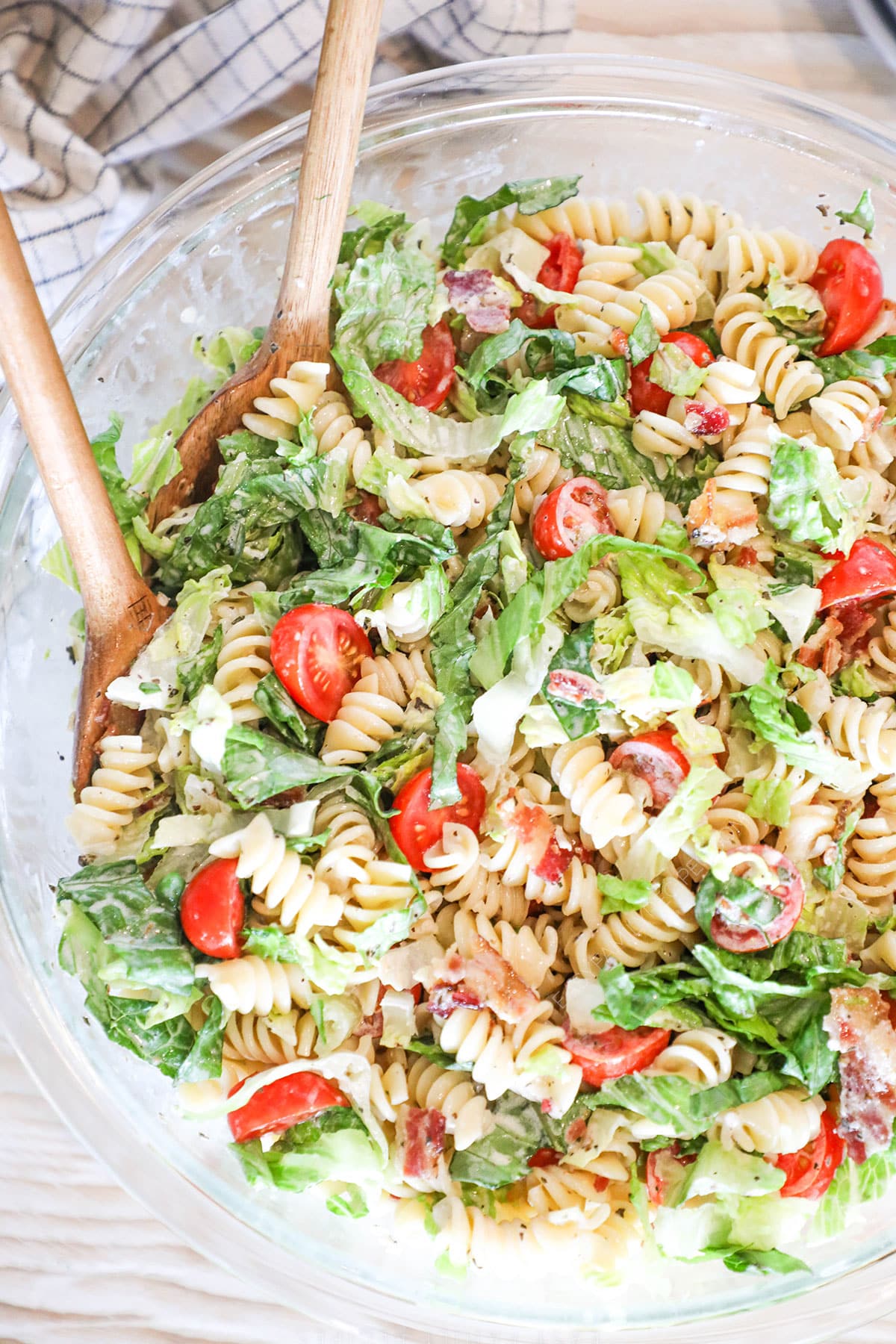 above image of pasta salad in a bowl with salad tongs.