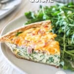 A slice of ham and spinach quiche on a white plate with a salad alongside. The text reads, "ham and spinach quiche"