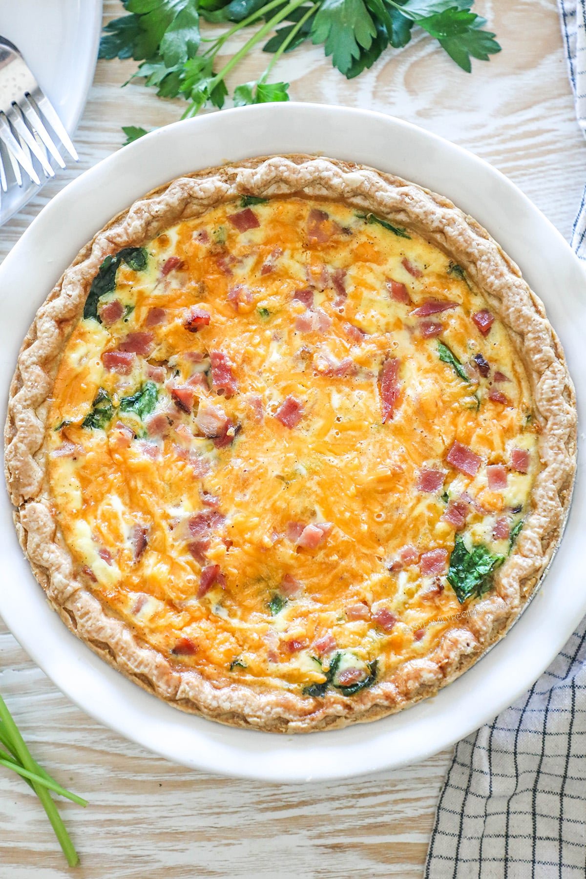 Top view of a ham and spinach quiche in a white pie plate. Step 6 for how to make ham spinach quiche.