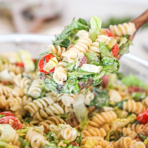 a scoop of pasta salad being taken out of a bowl.