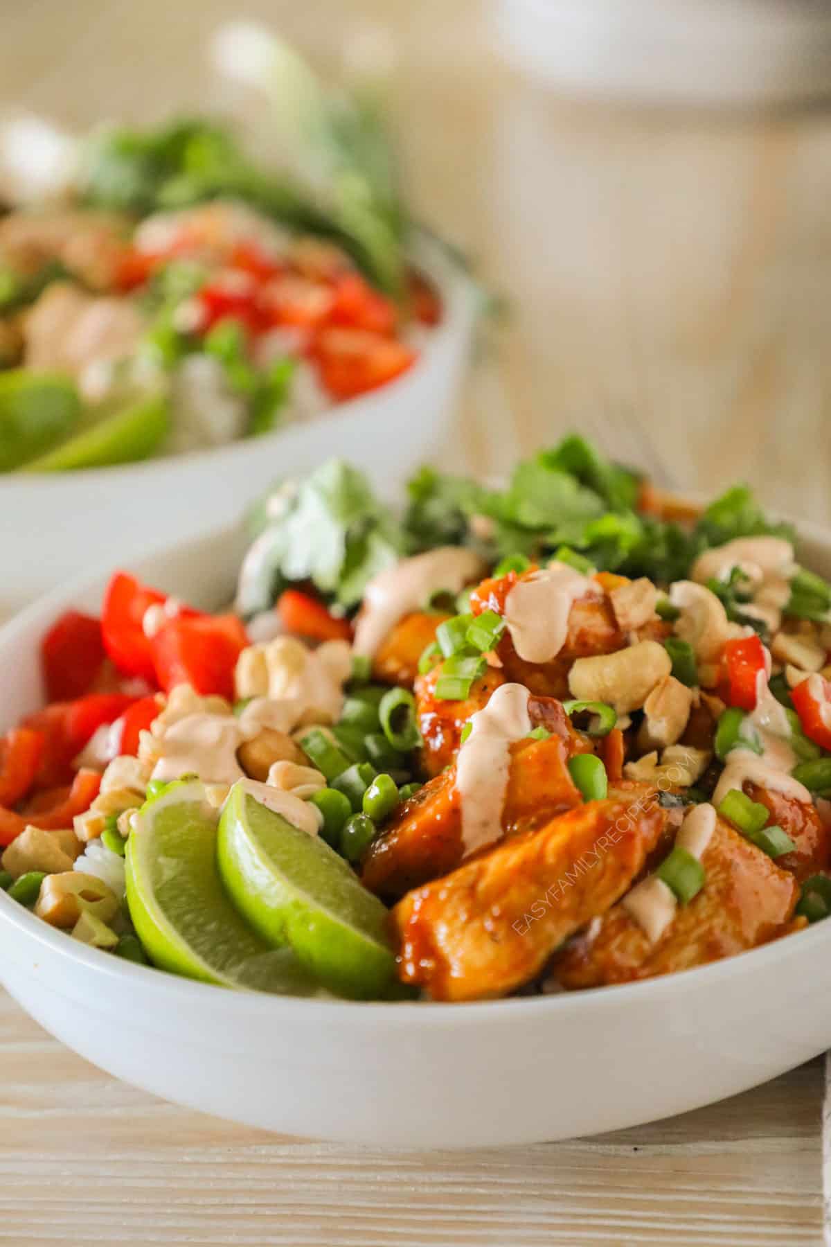 Easy chili crunch chicken bowl assembled in a bowl with dressing drizzled on top.