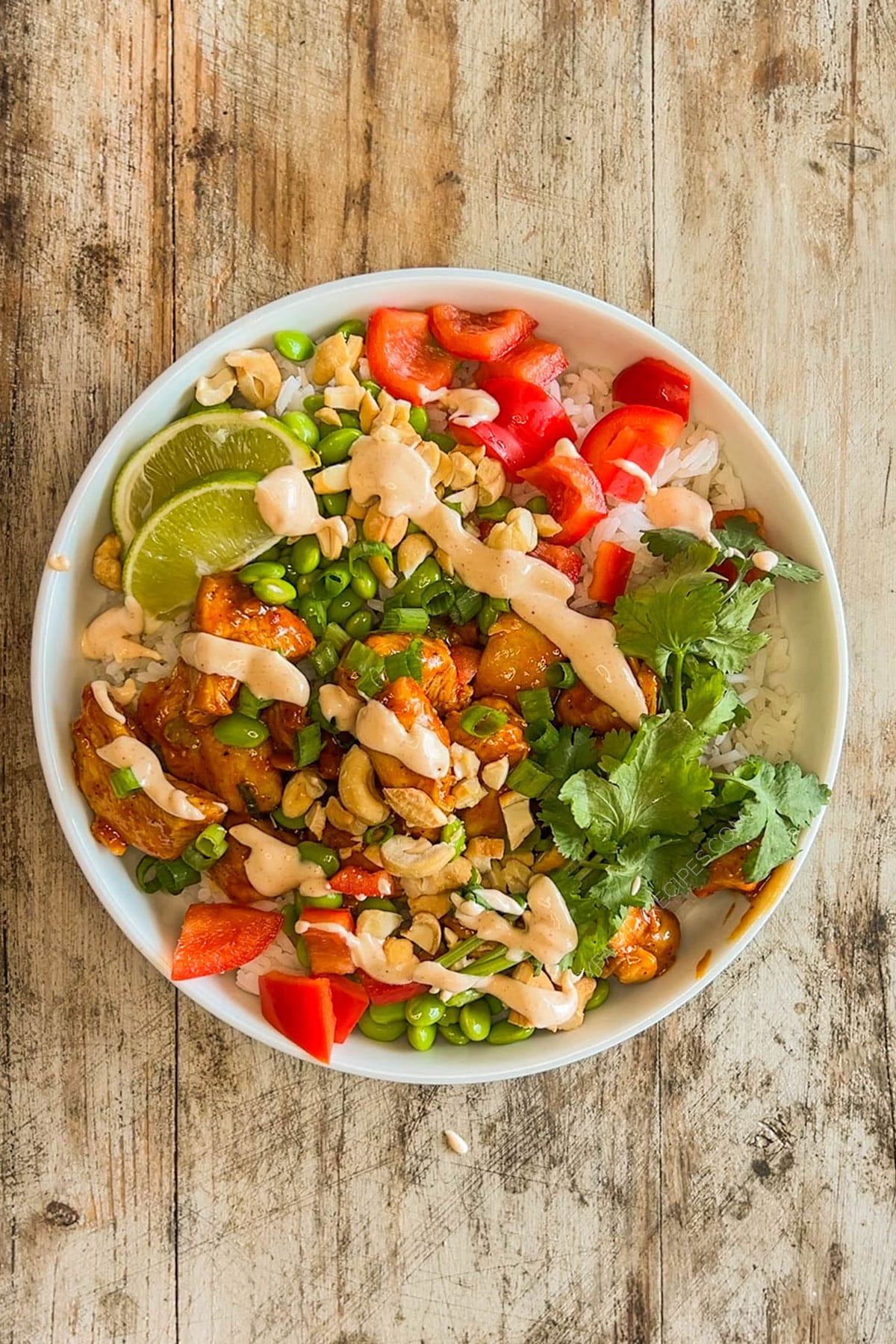 Easy chili crunch chicken bowl assembled in a bowl with dressing drizzled on top.