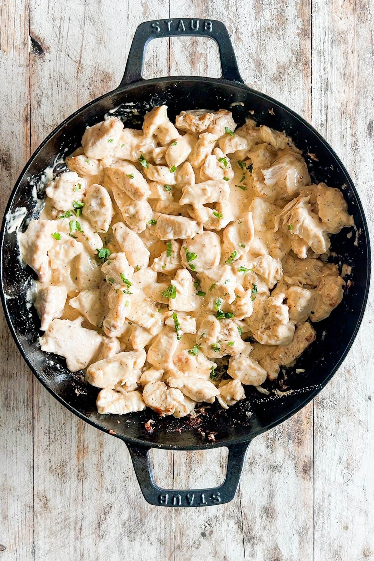 cooked chicken coated in bang bang sauce in a skillet.
