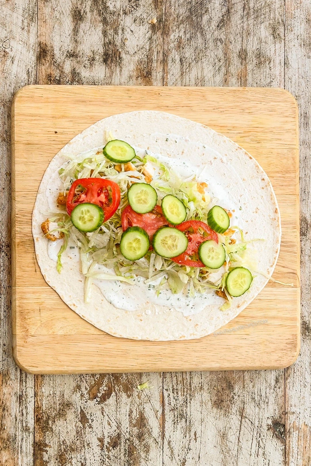 Step two for making chicken tender wraps: Top with veggies.