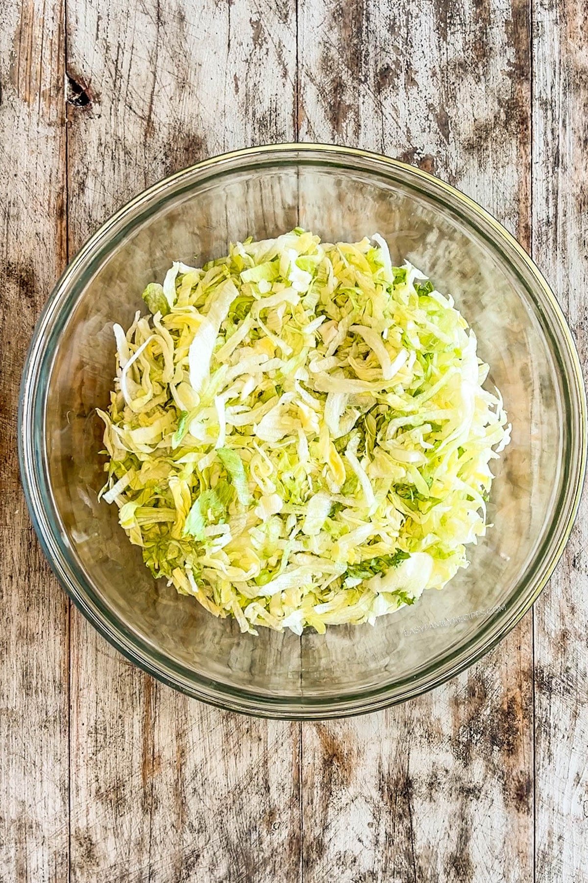 Lettuce is added to the bowl for layered taco salad