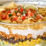 A close-up of layered taco salad in a glass bowl. The text reads, "layered taco salad"