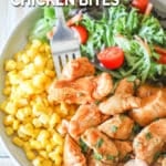 Top view of a white plate full of honey BBQ chicken bites, corn, and a simple green salad with a silver fork. The text reads, "Honey BBQ Chicken Bites"