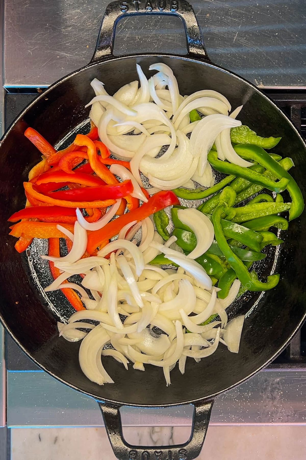 Peppers and onions in a skillet for chicken fajita tacos.