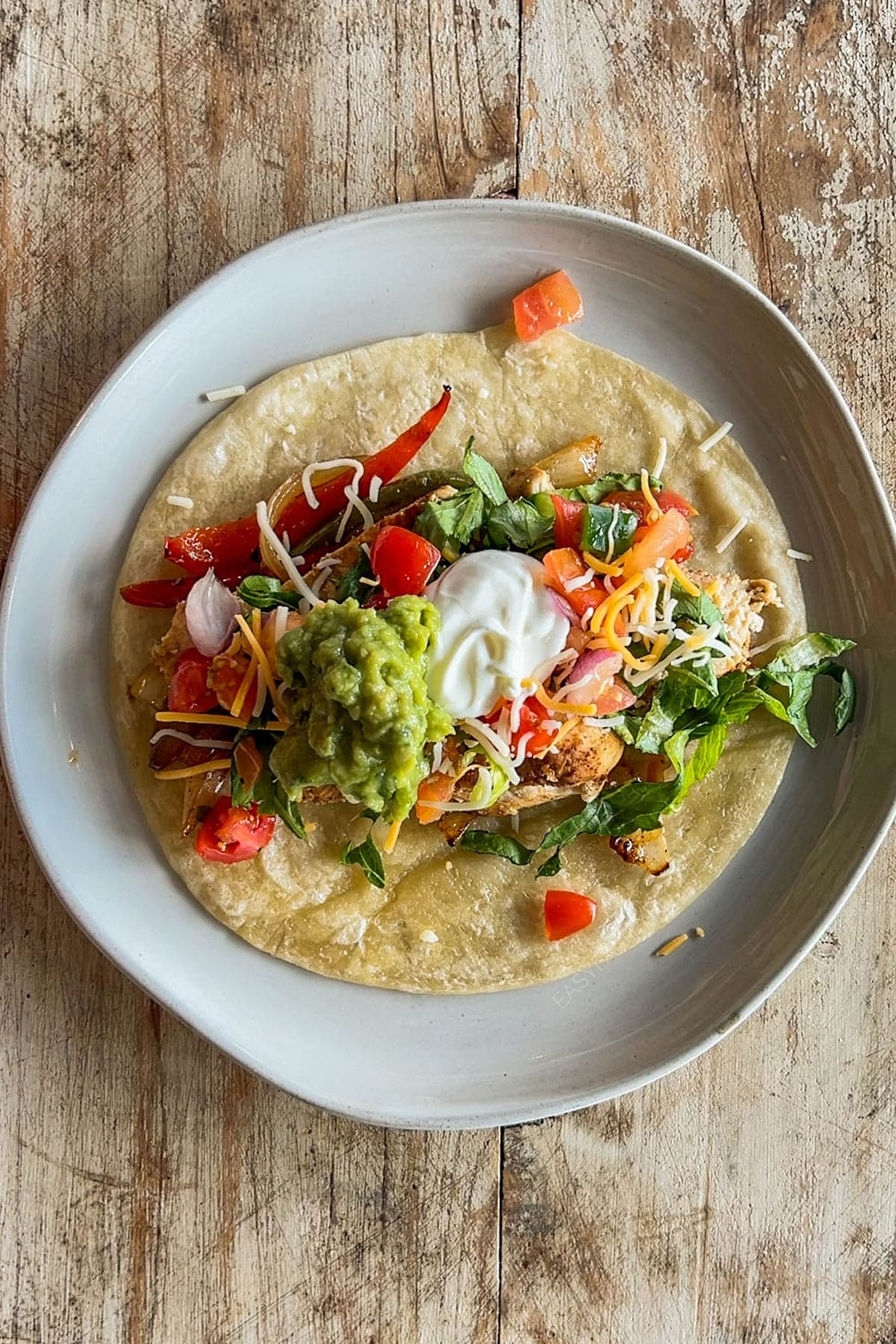 Top view of a chicken fajita taco being assembled.