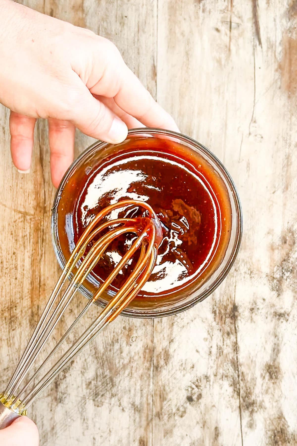 Mixing up the BBQ sauce and honey with a silver whisk for Honey BBQ Chicken Bites.