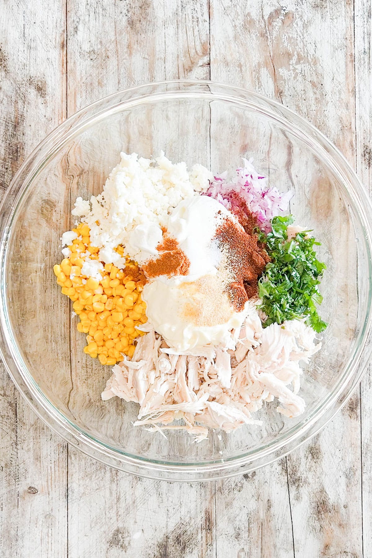 Spices added to the ingredients for Street Corn Chicken Salad in a mixing bowl