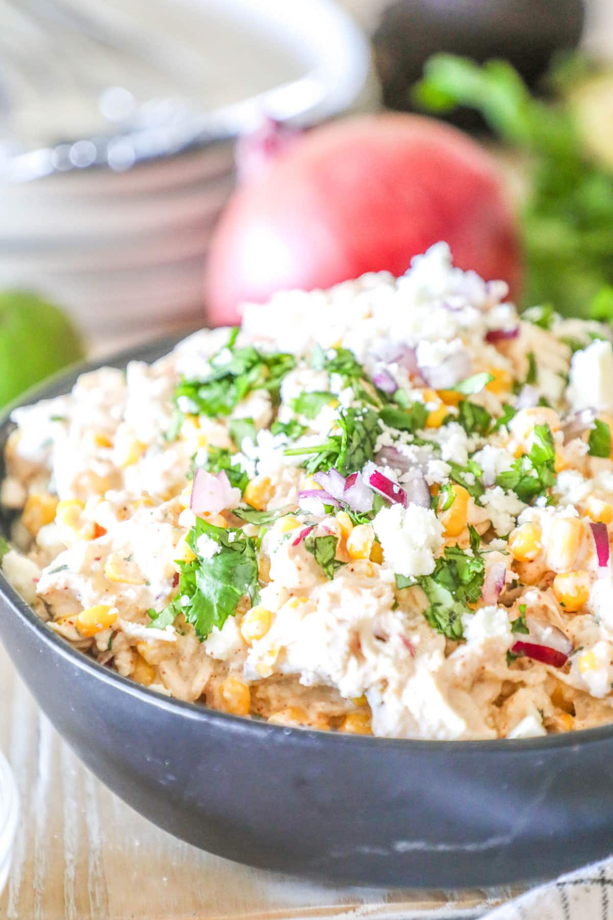 A gray bowl full of Street Corn Chicken Salad on a distressed wooden background. 