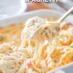 A serving spoon scoops a portion of baked chicken spaghetti out of the casserole dish. The text reads, “Baked Chicken Spaghetti”