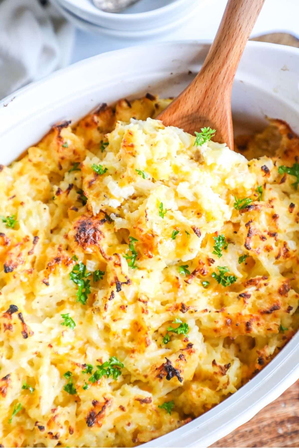 a scoop of hashbrown casserole being lifted from a casserole dish