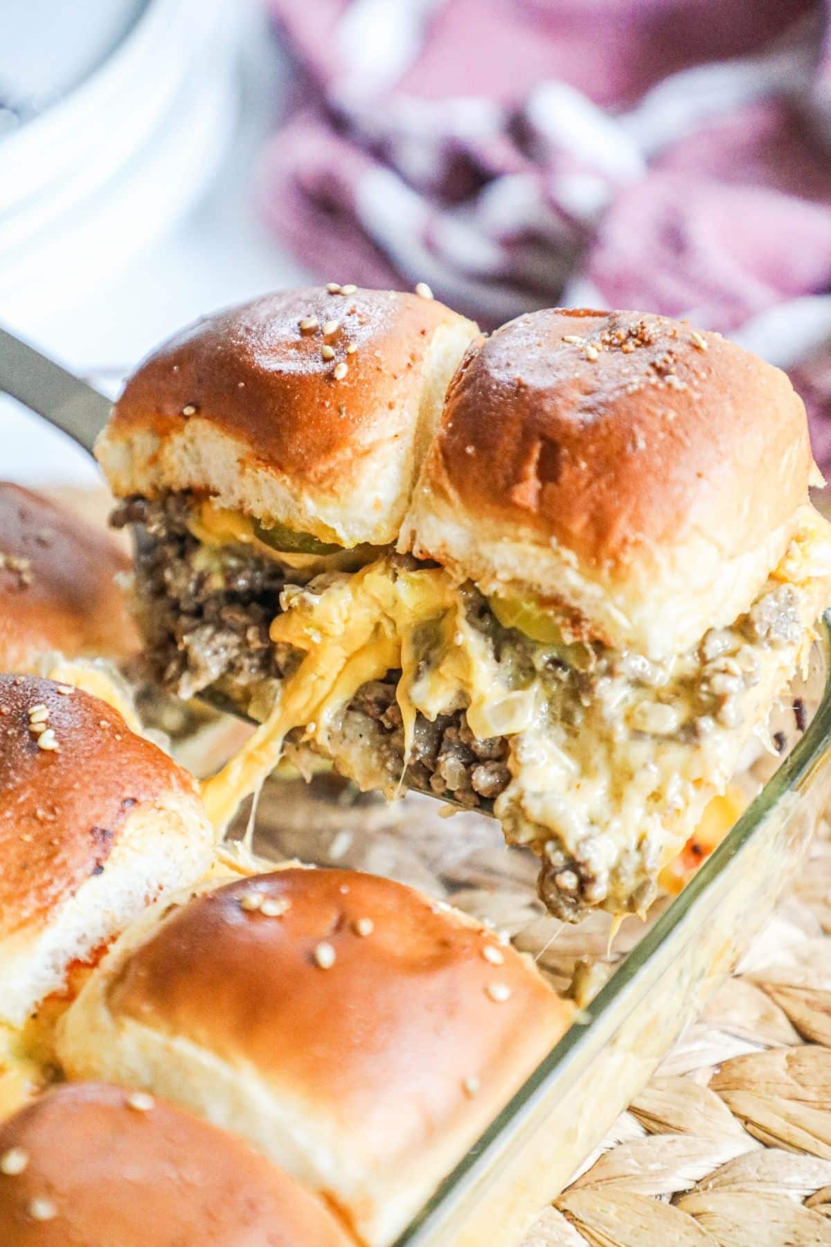 2 cheeseburger sliders being lifted out of pan by a spatula