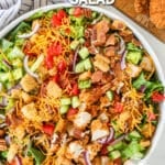 Top view of a white bowl full of chicken tender salad with cheddar cheese. The text reads, “Chicken Tender Salad”