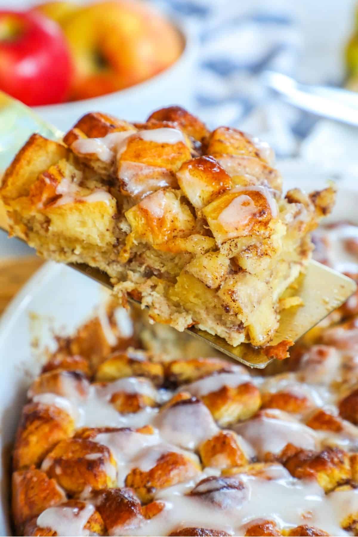 a serving of Cinnamon Roll casserole being scopped out of a casserole dish
