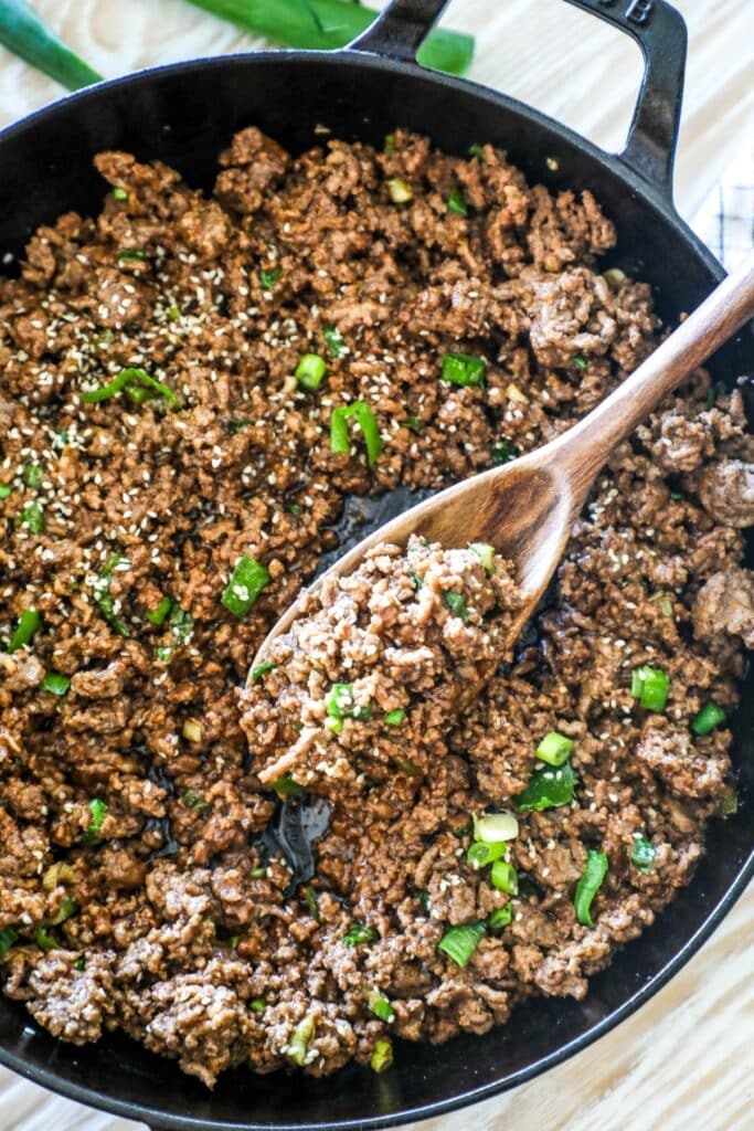 beef bulgogi in a cast iron skillet topped with green onions and sesame seeds