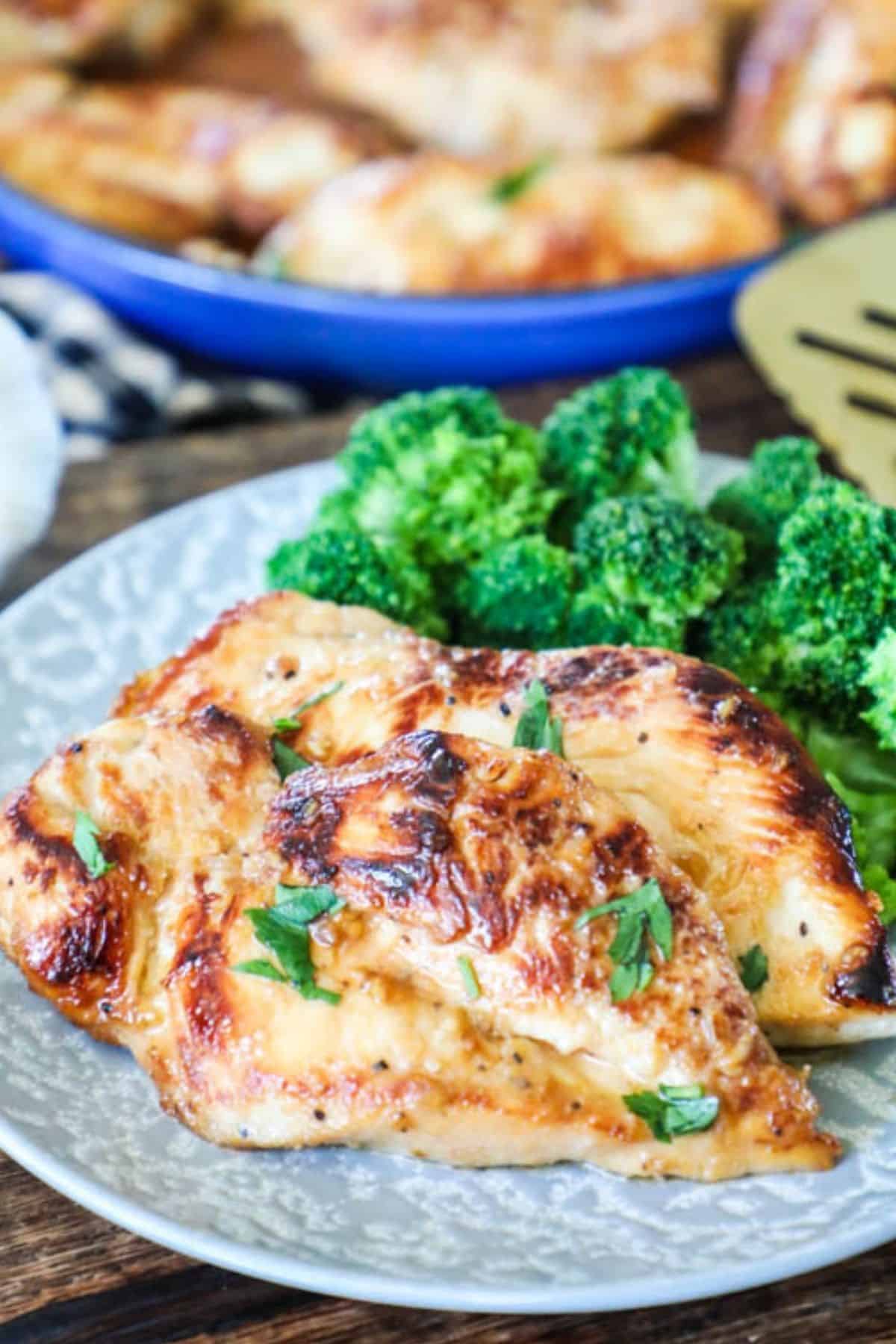 two chicken breasts on a plate with a side of broccoli