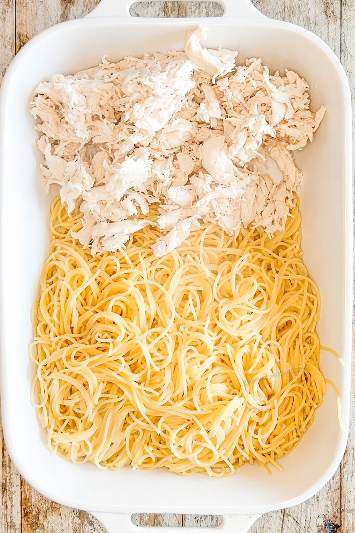 Step one for how to make baked chicken spaghetti: Add chicken and cooked pasta to casserole dish.