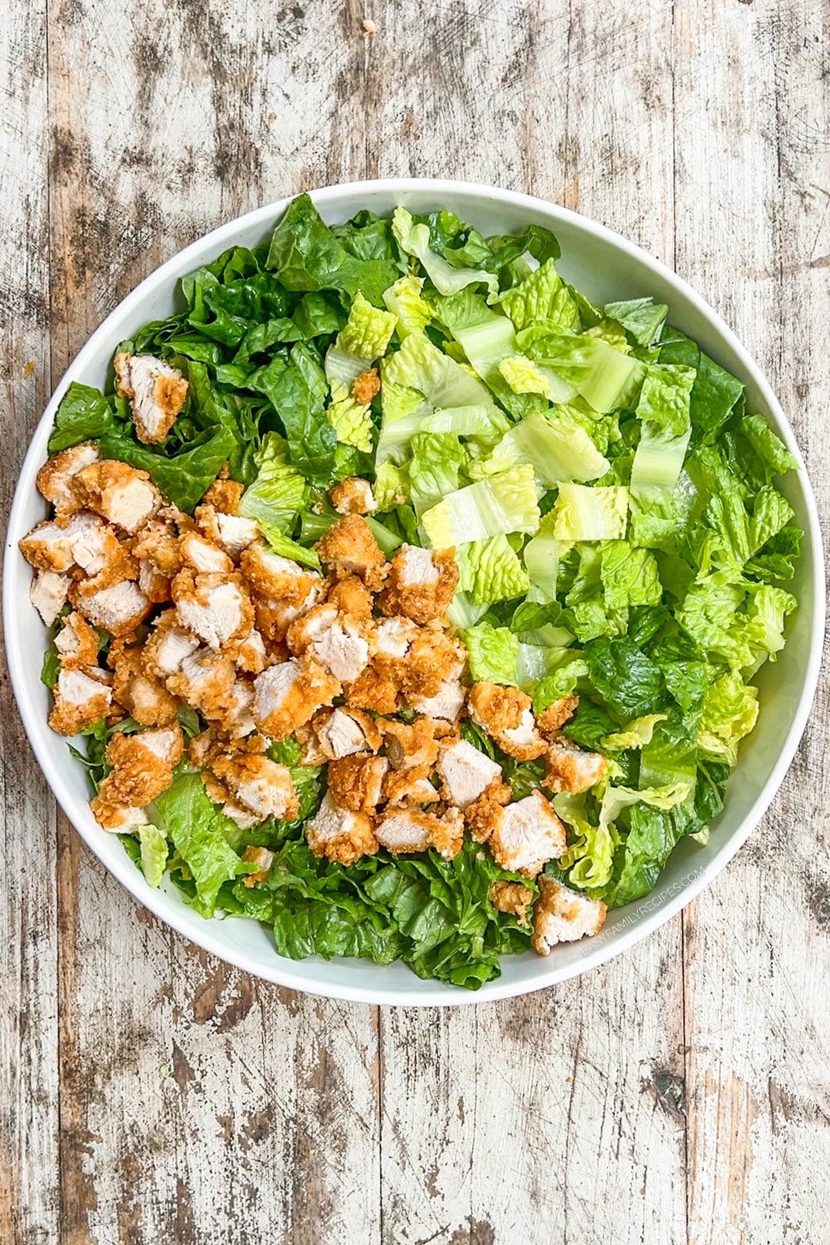 Step 2 for making chicken tender salad; add the chopped chicken tenders to the bowl.