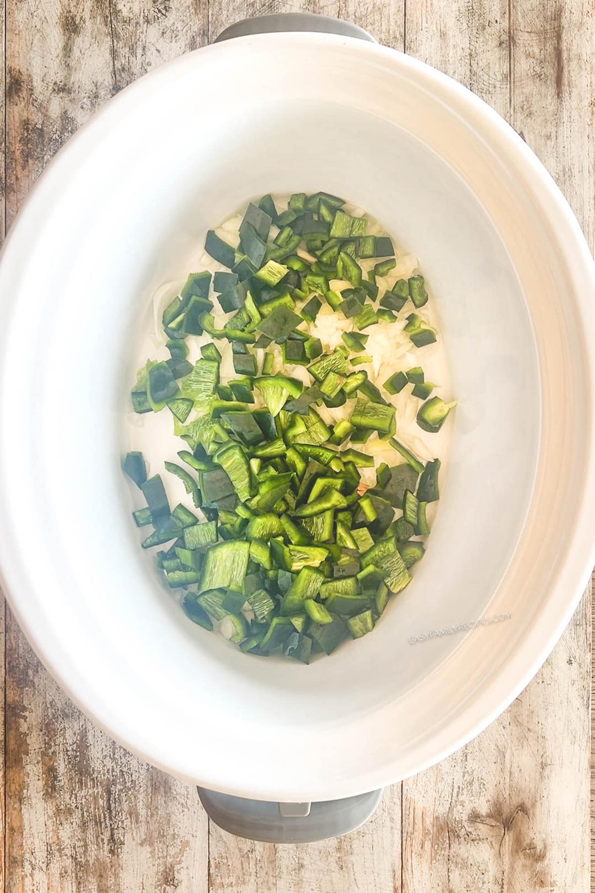 Step 2 for making Crockpot Pork Chile Verde: Add the diced poblano peppers to the pot.