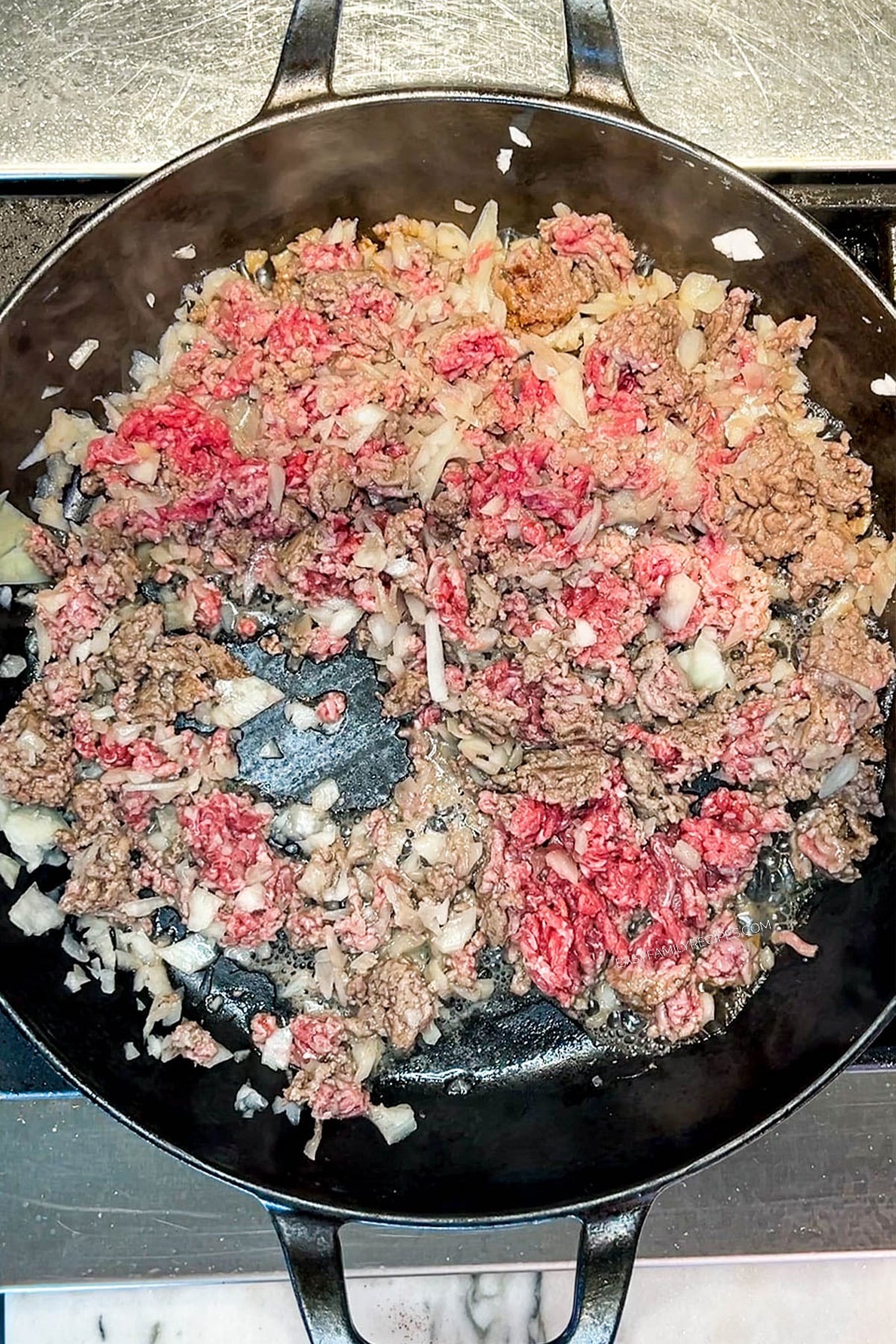 beef and onion being cooked in a skillet.