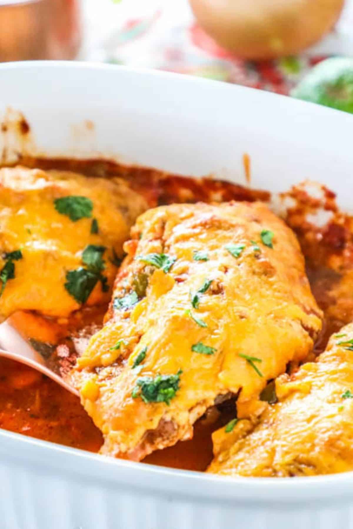 salsa chicken breasts topped with melted cheddar cheese in a white baking dish